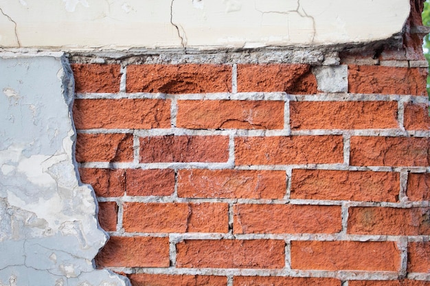 Grietas y deterioro en una pared de ladrillo con enlucido